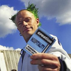 a man with green hair holding up a cell phone