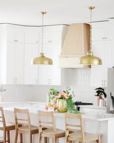 a kitchen with white cabinets and gold pendant lights