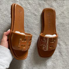 "The Sport Slide Is Made Of Soft Padded Leather That Hugs The Foot, With A Cushioned Foam Insole For Flexible Support. The Raised Double T Is Edged In Metallic Trim For Subtle Shine." Preowned, Only Worn Once - Size 7 - Color: Bourbon Miele / Gold - Comes With Box, Original Packaging, & Dustbag - Padded Napa Leather Upper - Metallic Calfskin Trim - Cushioned Insole Will Trade For The Cream Or Black Ones Tory Burch Slippers, Black Wedge Flip Flops, Tory Burch Slides, Tory Burch Sandal, Tan Leather Sandals, Pretty Sandals, Pretty Shoes Sneakers, Fashion Shoes Heels, Miller Sandal