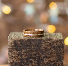 two wedding bands sitting on top of a wooden block with blurry lights in the background