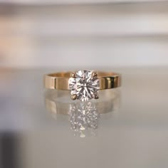 a diamond ring sitting on top of a white table with reflection in it's surface