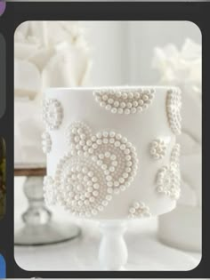 an image of a white cake with pearls on the icing and decorations around it