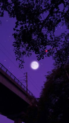 the moon is shining brightly in the night sky over a bridge with power lines above it