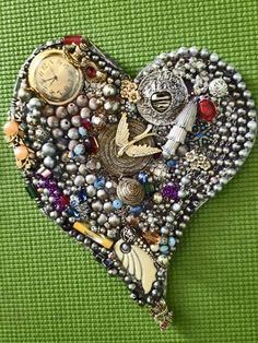 a heart shaped brooch with many different things on it's side and a clock in the middle