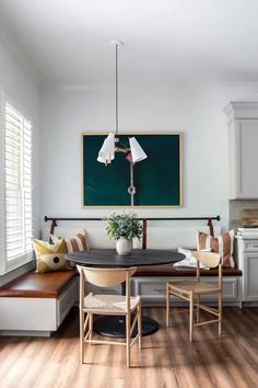 a dining room table with chairs and a bench in front of a chalkboard on the wall