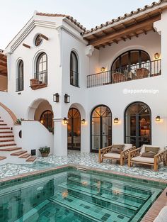 an indoor swimming pool in front of a large white house with stairs leading up to it