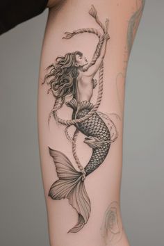 a woman's leg with a tattoo on it and an image of a mermaid