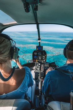 two people sitting in the cockpit of an airplane looking at the water from above them