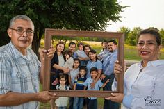 a group of people standing around each other holding up a picture frame in front of them