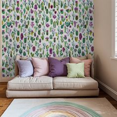 a white couch sitting in front of a wall covered in colorful cactus print wallspaper