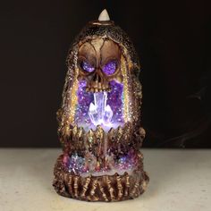 a lit up candle with a skull on it's head and purple lights in its eyes