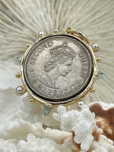 a close up of a coin with pearls on it's head and in front of a flower