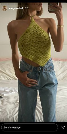 a woman taking a selfie with her cell phone while wearing high waist jeans and a halter top