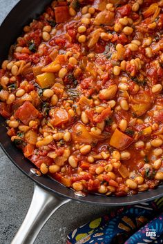 a pan filled with beans and vegetables on top of a table