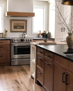 a kitchen with wooden cabinets and stainless steel appliances in the center, along with wood flooring