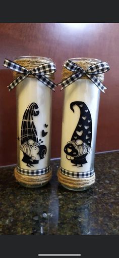 two jars with designs painted on them sitting on a counter