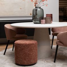 a round table with two chairs and a vase on top, in the middle of a living room