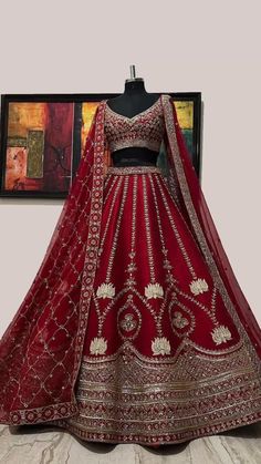 a red lehenga is displayed in front of a painting