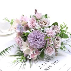 a bouquet of flowers sitting on top of a table next to a cup and saucer