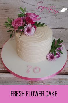 a white cake with pink flowers on top and the words fresh flower cake above it