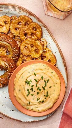 a plate with onion rings and dip on it next to some pretzel slices