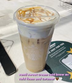 a cup of iced coffee with caramel swirl on the top sits next to a cd