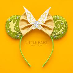 a mouse ears headband with green and gold glitters on it's ears