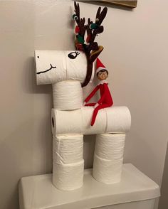 the elf is sitting on top of the toilet paper roll sculpture, which looks like a reindeer