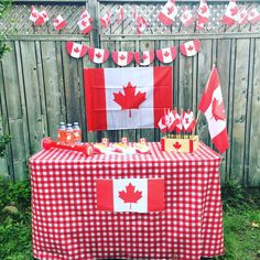 a red and white checkered table cloth with canadian flag decorations on it in front of a fence