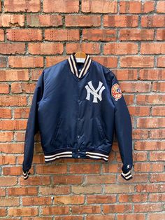 a new york yankees baseball jacket hanging on a brick wall in front of a brick wall