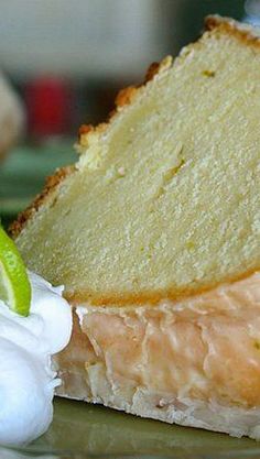 a piece of cake sitting on top of a plate with whipped cream and a lime