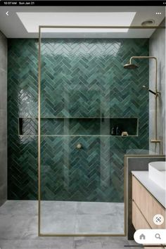 a bathroom with green tiles on the walls and floor, along with a walk in shower