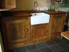 a white sink sitting under a wooden counter top next to a vase filled with flowers