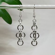 Modern silver metal links earrings complement any outfit, dressed up or dressed down. Thick, sturdy 6mm and 8mm metal rings make up these circular patterned earrings, arranged for a chain-like appearance.  The rings are suspended from metal fish hook-style ear wires.  Clear plastics earring backs are included. Approximate dangle length: 2" (see photo). Approximate width: 1/2". Metal links dangle and move freely. Please note, photos are representative only; your exact earrings may not appear in t Metal Link Earrings For Gifts, Single Link Earring In Metal, Silver Sterling Link Earrings, Silver Link Sterling Silver Earrings, Silver-plated Wire Beaded Drop Earrings, Modern Link Shaped Metal Earrings, Trendy Nickel-free Dangle Chandelier Earrings, Hypoallergenic Metal Circle Earrings, Nickel-free Dangle Earrings Made Of Alloy