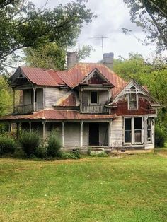 an old run down house with rusted tin roof in the middle of a field