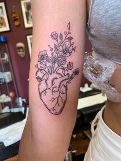 a woman's arm with a heart and flowers tattoo on it