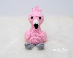 a crocheted pink bird sitting on top of a white furnishing floor