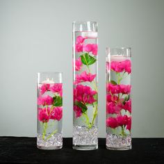 three tall vases with pink flowers in them