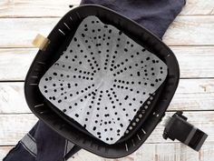 a black and white basket on top of a wooden floor next to a blue towel