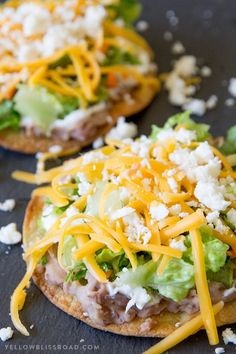 two pizzas with cheese, lettuce and other toppings