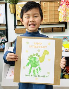 a young boy holding up a card that reads happy father's day, dad youre dino - mitt