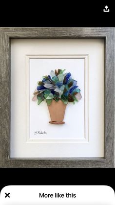 a small potted plant with blue and green flowers in it's center is framed