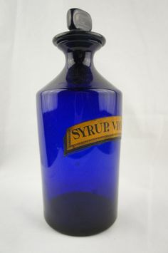 a blue glass bottle sitting on top of a white table next to a black lid