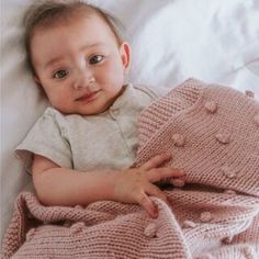 a baby wrapped in a blanket on top of a bed