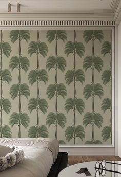 a bedroom with palm trees on the wall next to a bed and coffee table in front of it