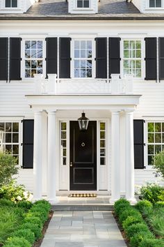 a white house with black shutters on the front door