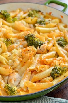 pasta with chicken and broccoli in a green skillet on a wooden table