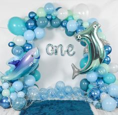 the balloon arch is decorated with blue, white and silver balloons that spell out one