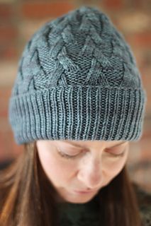 a woman wearing a knitted hat looks down at her cell phone