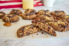 chocolate chip cookies with pecans and almonds on parchment paper next to a glass of milk